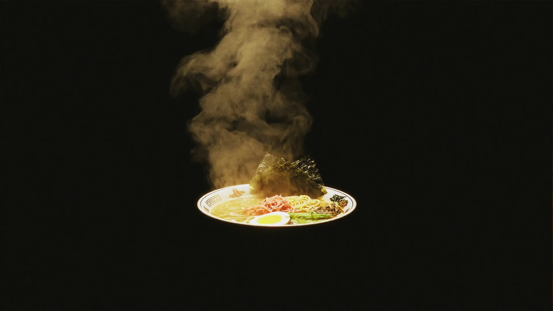 A steaming ramen bowl lit from above, emerging from darkness