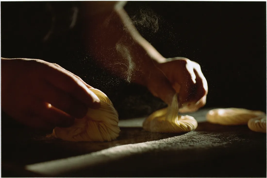 Flour-dusted hands folding fresh ramen noodles